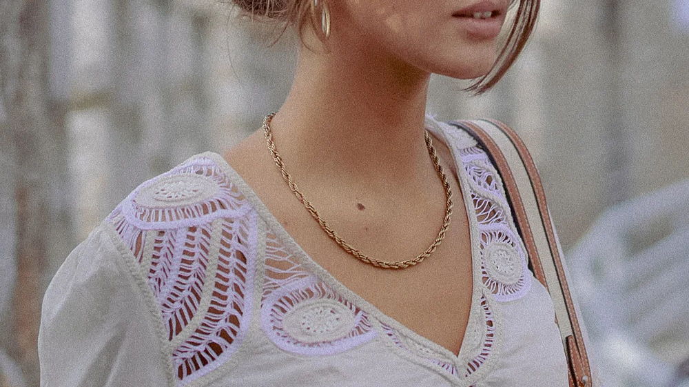 Model wearing a silk cream blouse with intricate neck and shoulder embroidery