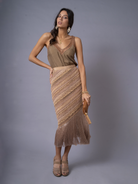 A model wearing an OCHRIDIA Fringe Skirt with a long rayon fringe in an earthy color, paired with a brown top and tan sandals.