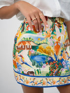 Asymmetrical faux wrap mini skirt featuring exclusive vibrant and picturesque textile print. Close up view shown.